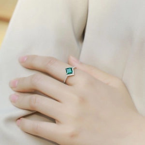 Princess cut emerald ring in S925 sterling silver worn on a hand against neutral background