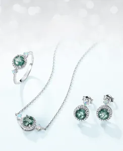 Detailed set of moss agate jewelry with ring, pendant necklace and earrings on blue bokeh