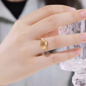 Macro view of a pear-cut yellow crystal ring with side diamonds on a gold band