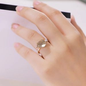 Close-up of elegant gold ring with pear-cut yellow gemstone and side diamonds on finger