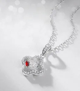 Detailed close-up of a silver four-leaf clover pendant with red ruby and white zircon