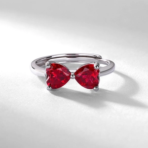 Silver bow heart ring featuring red lab-grown rubies in an adjustable open band design