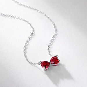 S925 silver bow necklace with ruby red heart gemstones for women on light gray surface