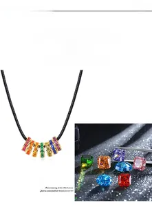 Close-up of rainbow cubic zirconia slider pendant on black cord with assorted colorful gems