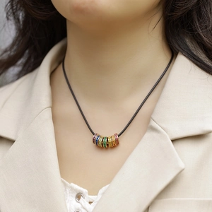 Rainbow cubic zirconia cylinder pendant necklace on black cord worn by a model