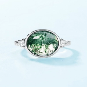 Vintage oval moss agate silver ring with side zircon stones on light blue background