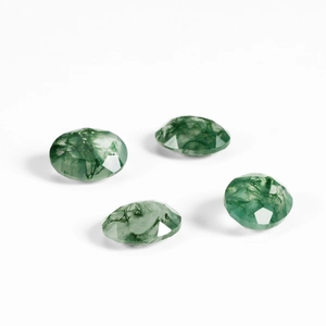 Detailed view of four oval faceted green moss agate gemstones with natural inclusions
