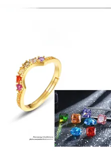 Macro detail of V-shaped gold ring featuring colorful cubic zirconia and engraved patterns