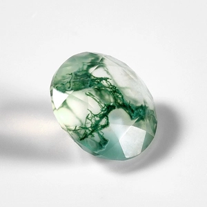 Macro shot of oval faceted moss agate gemstone with natural green moss inclusions