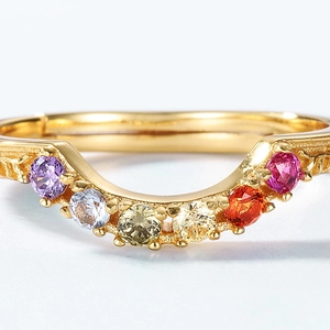 Elegant gold V-shaped ring with multi-colored gemstones and detailed relief engraving