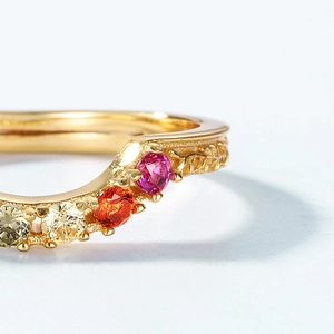 Macro shot of V-shaped gold ring with multi-color zircons and engraved leaf texture