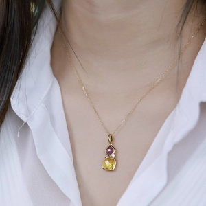 Detail of s925 silver necklace with square purple and yellow gemstone pendant on neck