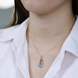 Detail of S925 silver necklace with pink and blue square gemstones on a model