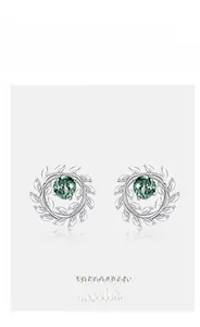 Macro view of silver olive leaf stud earrings featuring natural green moss agate stones