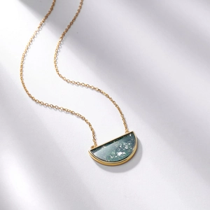 Elegant gold necklace with a semicircular green moss agate pendant on a white background