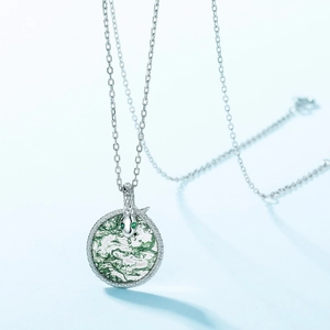 S925 silver coiled snake necklace featuring a green moss agate stone pendant on blue