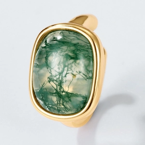 Vintage gold ring featuring oval moss agate stone in a bezel setting on gray background