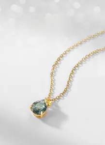 Detail of pear-cut moss agate pendant with natural green texture in gold claw setting