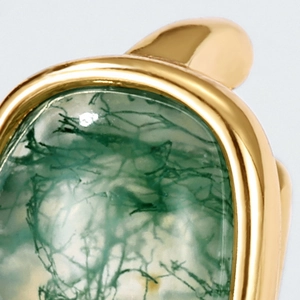 Macro view of natural green moss agate stone set in polished gold-plated ring band