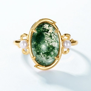 Vintage gold ring with oval moss agate stone and two side pearls on a light background