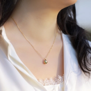 Elegant gold-plated pear-cut moss agate pendant necklace on a model's neck