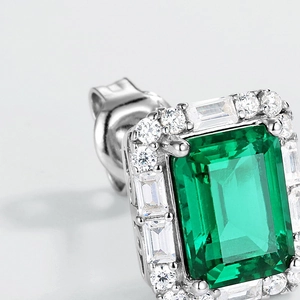 Macro detail of emerald-cut green gemstone earring with baguette diamond halo setting