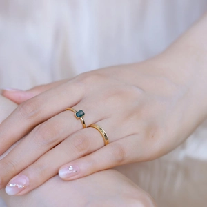 Detail of 925 silver gold plated rings with rectangular green moss agate on fabric