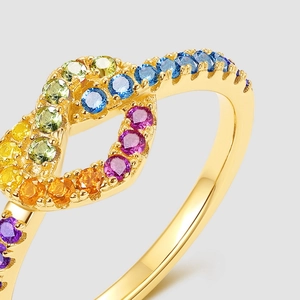 Macro detail of gold-plated infinity ring featuring micro-set gradient rainbow gemstones