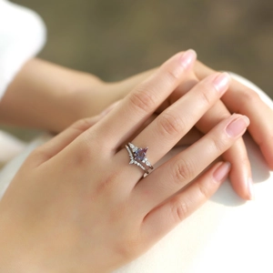 Kite-cut alexandrite ring set with V-shaped diamond band on hand in natural light