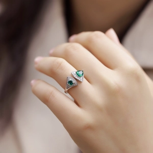 Macro detail of fan-shaped S925 silver ring with heart-cut emerald stones and micro diamonds