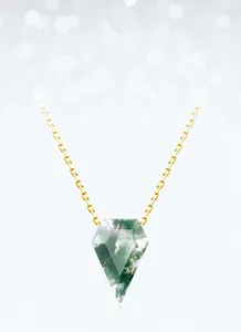 Close-up of golden necklace with pentagonal moss agate pendant on bokeh background