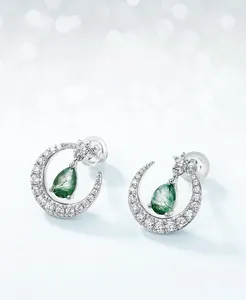 Macro detail of moon-shaped silver stud earrings with sparkling moss agate teardrops