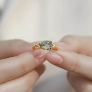 Macro detail of a pear-cut moss agate gemstone set in a vintage gold-plated silver ring