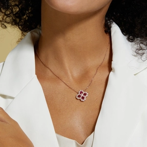 Dettaglio della collana a quadrifoglio con gemme rosse e catena in oro rosa su modella