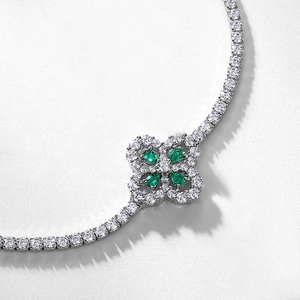 Elegant silver four-leaf clover bracelet with pear-cut emerald gems and diamonds