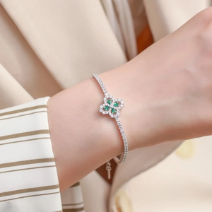 Dettaglio di un bracciale a quadrifoglio in argento con smeraldi verdi al polso