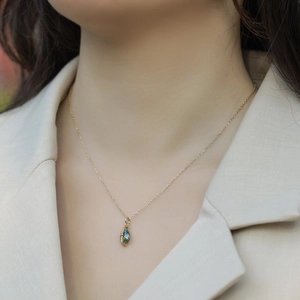 Detailed view of teardrop necklace with moss agate stone and pavé diamond halo on model