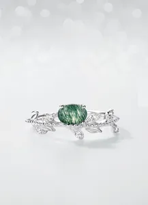 Detailed view of moss agate ring with silver olive branch band and sparkling zircon accents