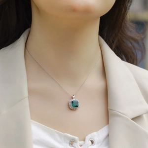 Pendentif émeraude élégant avec pierre carrée et chaîne argentée sur le cou du mannequin