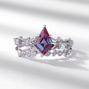 Detailed view of kite-cut alexandrite ring set with vine leaf silver band on white surface