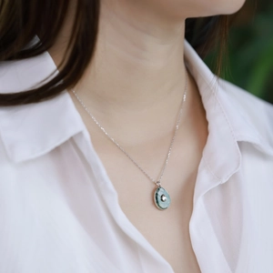 Close-up of a S925 silver necklace with a green moss agate teardrop pendant on a model