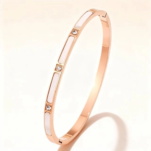 Macro detail of rose gold bangle featuring white enamel inlay and three clear crystals