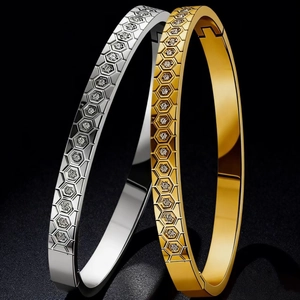 Gold and silver stainless steel honeycomb bangles with sparkling crystals on dark background