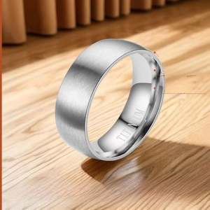 Detailed view of brushed silver titanium ring with inner engraving on wooden stand