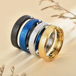 Nahaufnahme von vier matten Edelstahlringen in Schwarz, Blau, Silber und Goldoptik