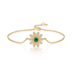 Bracelet marguerite doré avec pierre verte et zircons blancs sur une surface blanche