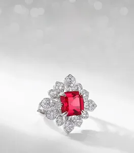 Close-up of square cut red lab ruby ring with sparkling diamond halo in floral design