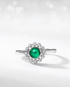 Close-up of cabochon synthetic emerald ring with a brilliant white zircon halo setting
