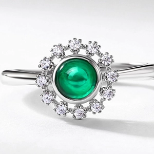 Macro shot of oval green emerald with white zircon halo on an S925 silver ring band