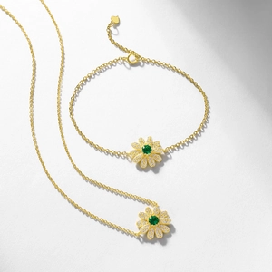 Daisy flower jewelry set with gold necklace and bracelet featuring green emerald stones